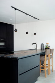 Moderne schwarze Pendelleuchte FAVORI in einer stilvollen Küche, aus der Seitenperspektive fotografiert.