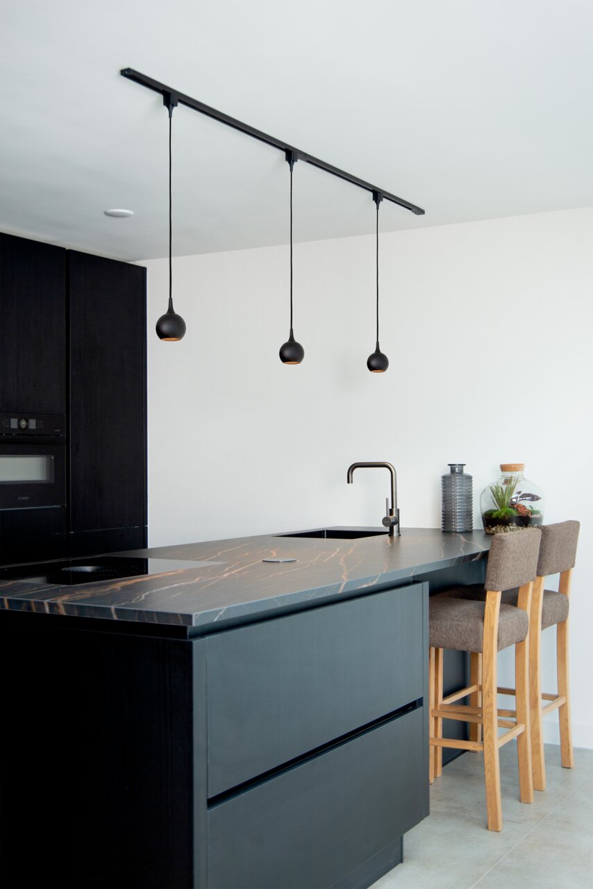 Moderne schwarze Pendelleuchte FAVORI in einer stilvollen Küche, aus der Seitenperspektive fotografiert.