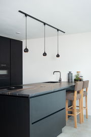 Moderne schwarze Pendelleuchte FAVORI in einer stilvollen Küche, aus der Seitenperspektive fotografiert.