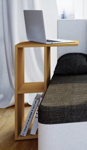 Schmaler, hellholzfarbener Beistelltisch mit Ablagefächern neben einem Bett, oben ein aufgeklappter Laptop; Ansicht seitlich in leichter Perspektive von vorn.