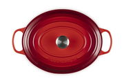 Roter ovaler Bräter von oben mit zwei Griffen und einem silbernen Knauf in der Mitte des Deckels.
