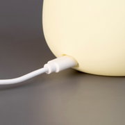 Close-up van een MANGO-nachtlampje op batterijen met aangesloten oplaadkabel.