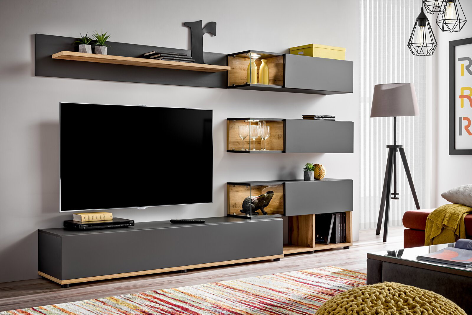 Moderne TV-Lowboard-Kombination in grauer Farbe mit Holzakzenten, bestehend aus mehreren Wandregalen und einem großen TV-Schrank, frontal betrachtet.