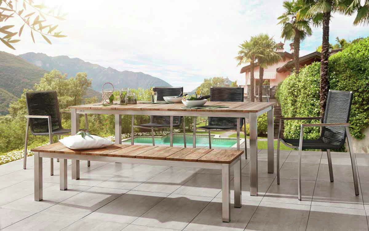 Gartenbank aus Holz und Metall auf einer Terrasse mit Blick auf einen Pool und Berge, seitliche Perspektive