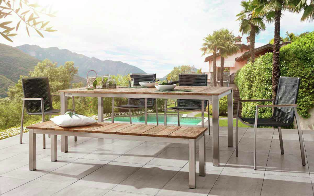 Gartenbank aus Holz und Metall auf einer Terrasse mit Blick auf einen Pool und Berge, seitliche Perspektive