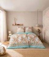 Bettwäsche-Set Estella SIENA in einem stilvoll eingerichteten Schlafzimmer, mit einem eleganten Paisley-Muster in Orange- und Grüntönen auf einem Bett mit zwei Kissen, aus der Perspektive von vorne aufgenommen.