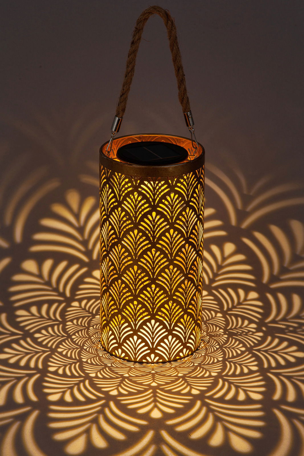 Solarbetriebene Laterne mit dekorativem Muster, das ein warmes Licht und faszinierende Schatten wirft, seitliche Perspektive