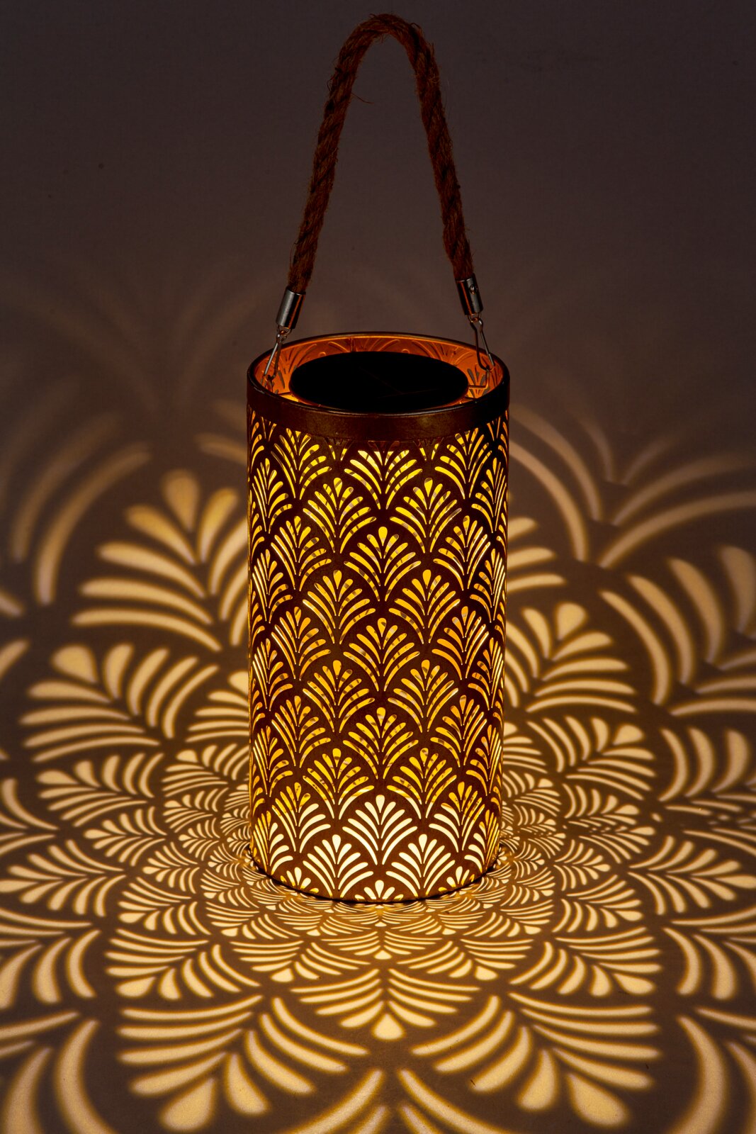 Zonne-energie-lantaarn met decoratief patroon dat een warm licht en fascinerende schaduwen werpt, zijaanzicht
