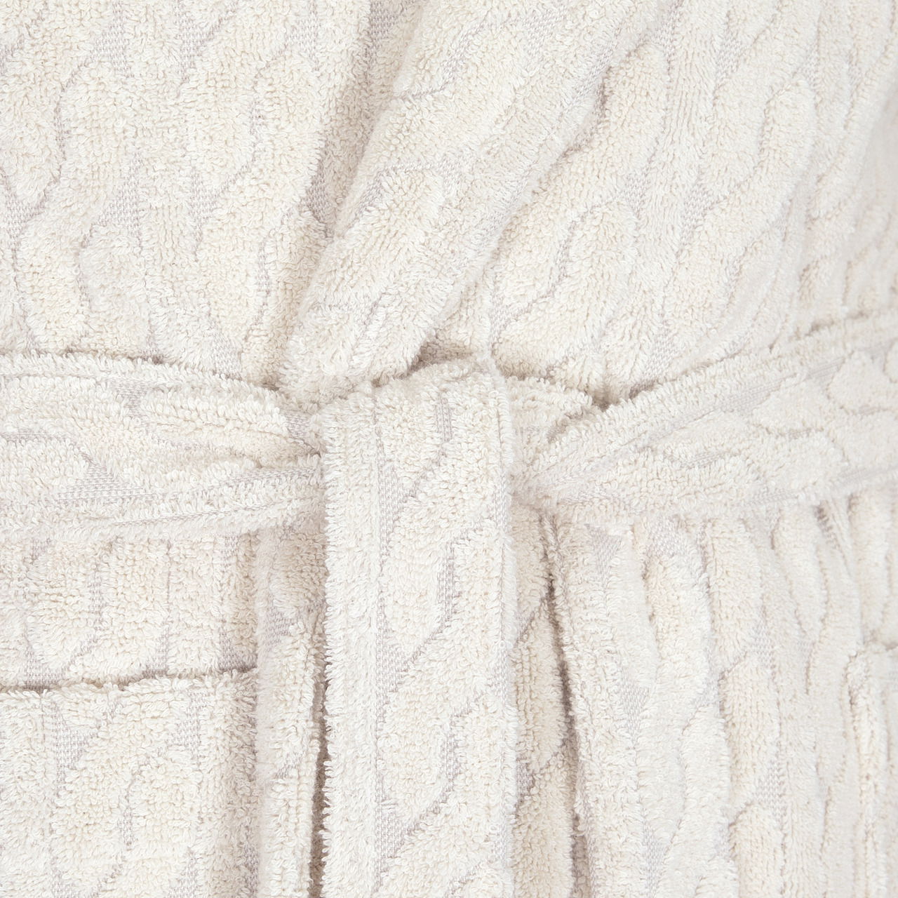 Nahaufnahme eines cremefarbenen Kapuzenmantels mit Gürtel und Strickmuster