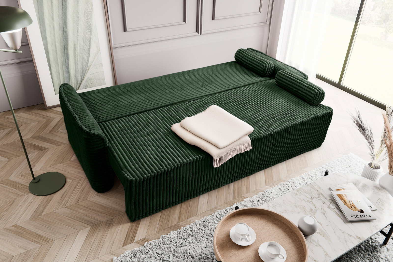 Grünes Schlafsofa in einem modernen Wohnzimmer, von oben fotografiert, mit einem beigen Überwurf und Kissen.