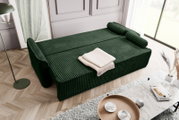 Grünes Schlafsofa in einem modernen Wohnzimmer, von oben fotografiert, mit einem beigen Überwurf und Kissen.