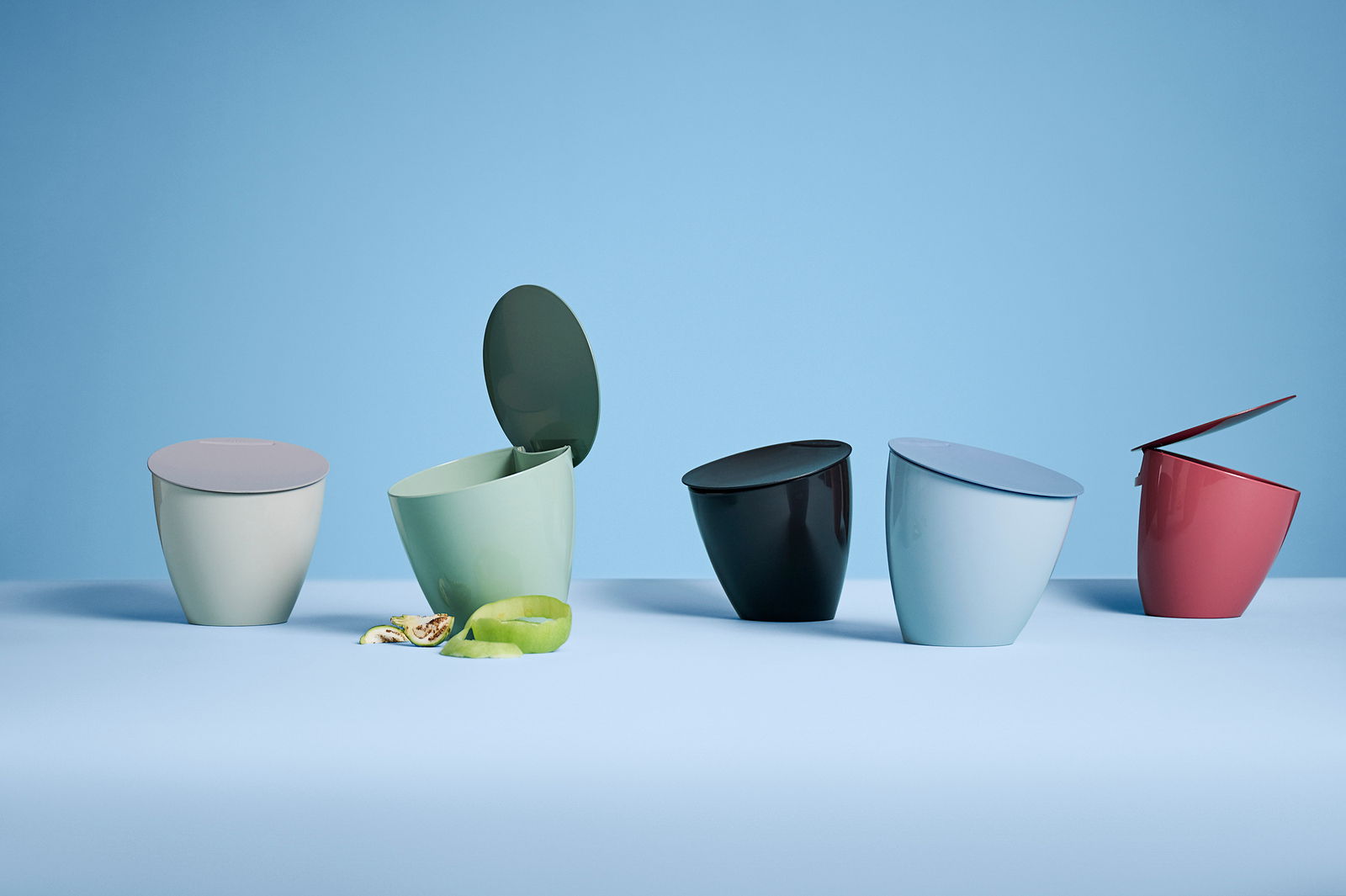 Mepal Bio-Abfallbehälter weiß Nordic white CALYPSO Fünf Bio-Abfallbehälter in verschiedenen Farben auf einer blauen Oberfläche, seitliche Perspektive.