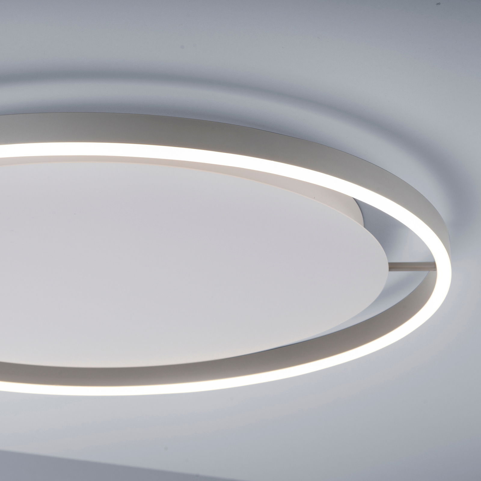 Moderne Deckenleuchte RITUS in seitlicher Perspektive mit kreisförmigem Design und leuchtendem Rand.
