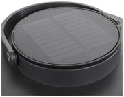 Nahaufnahme einer runden Solarlampe mit schwarzem Gehäuse und sichtbarem Solarpanel von oben.