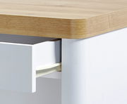 Nahaufnahme eines Schreibtisches mit Holzoberfläche und einer geöffneten weißen Schublade.