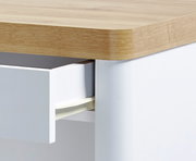 Nahaufnahme eines Schreibtisches mit Holzoberfläche und einer geöffneten weißen Schublade.