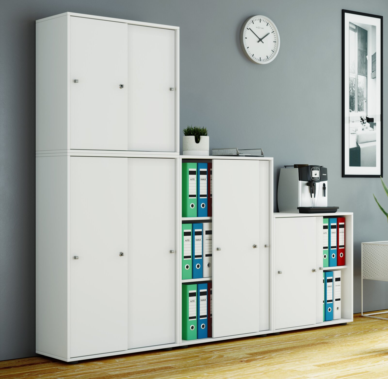 Modulares weißes Büroschranksystem mit Schiebetüren und offenen Regalfächern mit farbigen Ordnern, frontal aus leicht schräger Perspektive aufgenommen
