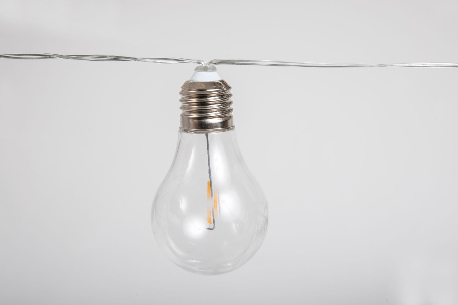 Nahaufnahme einer klaren Glühbirne an einer Girlande, seitliche Perspektive