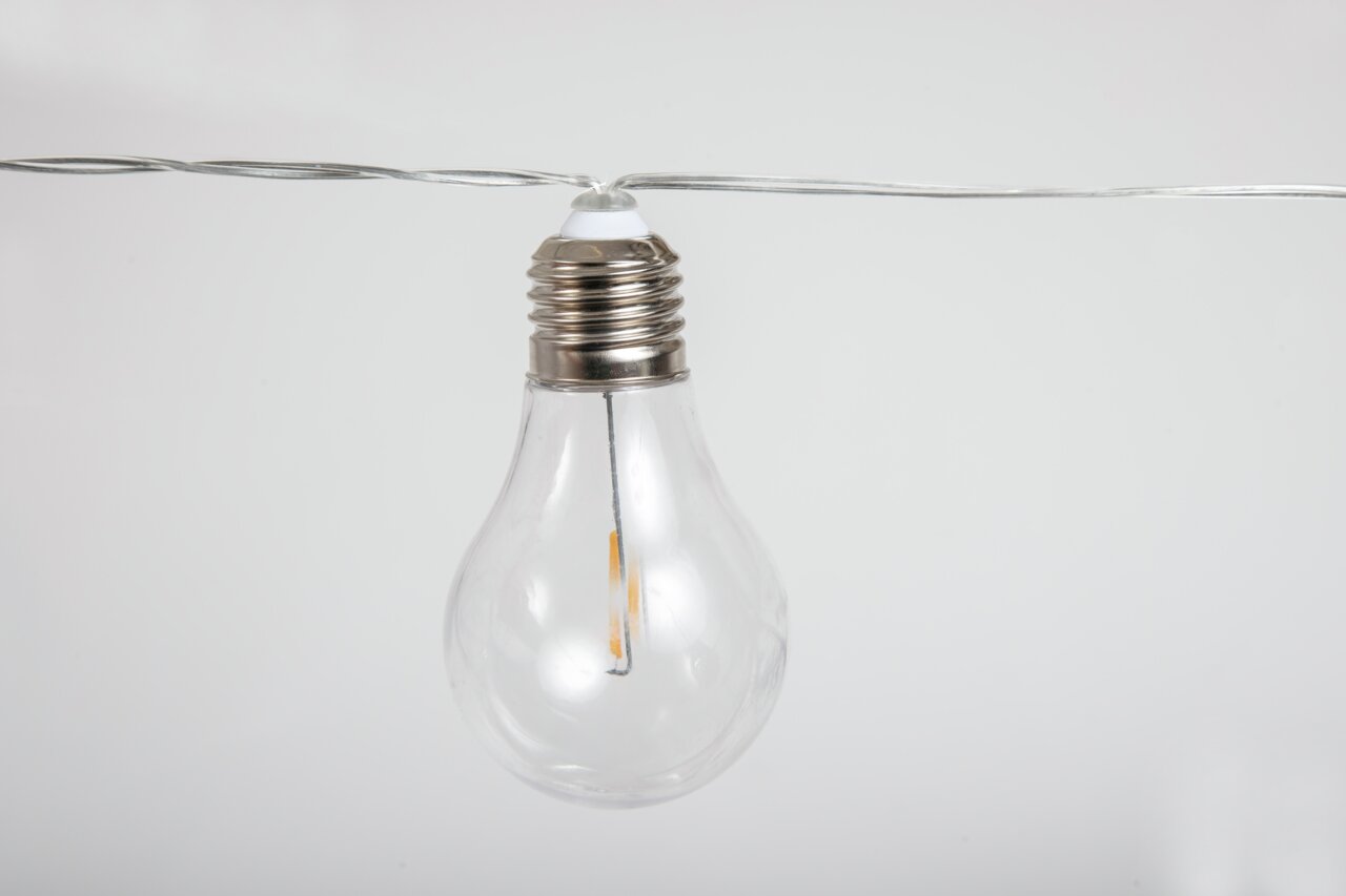 Nahaufnahme einer klaren Glühbirne an einer Girlande, seitliche Perspektive