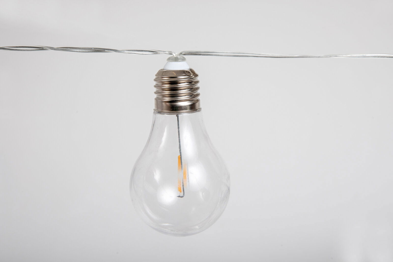 Nahaufnahme einer klaren Glühbirne an einer Girlande, seitliche Perspektive