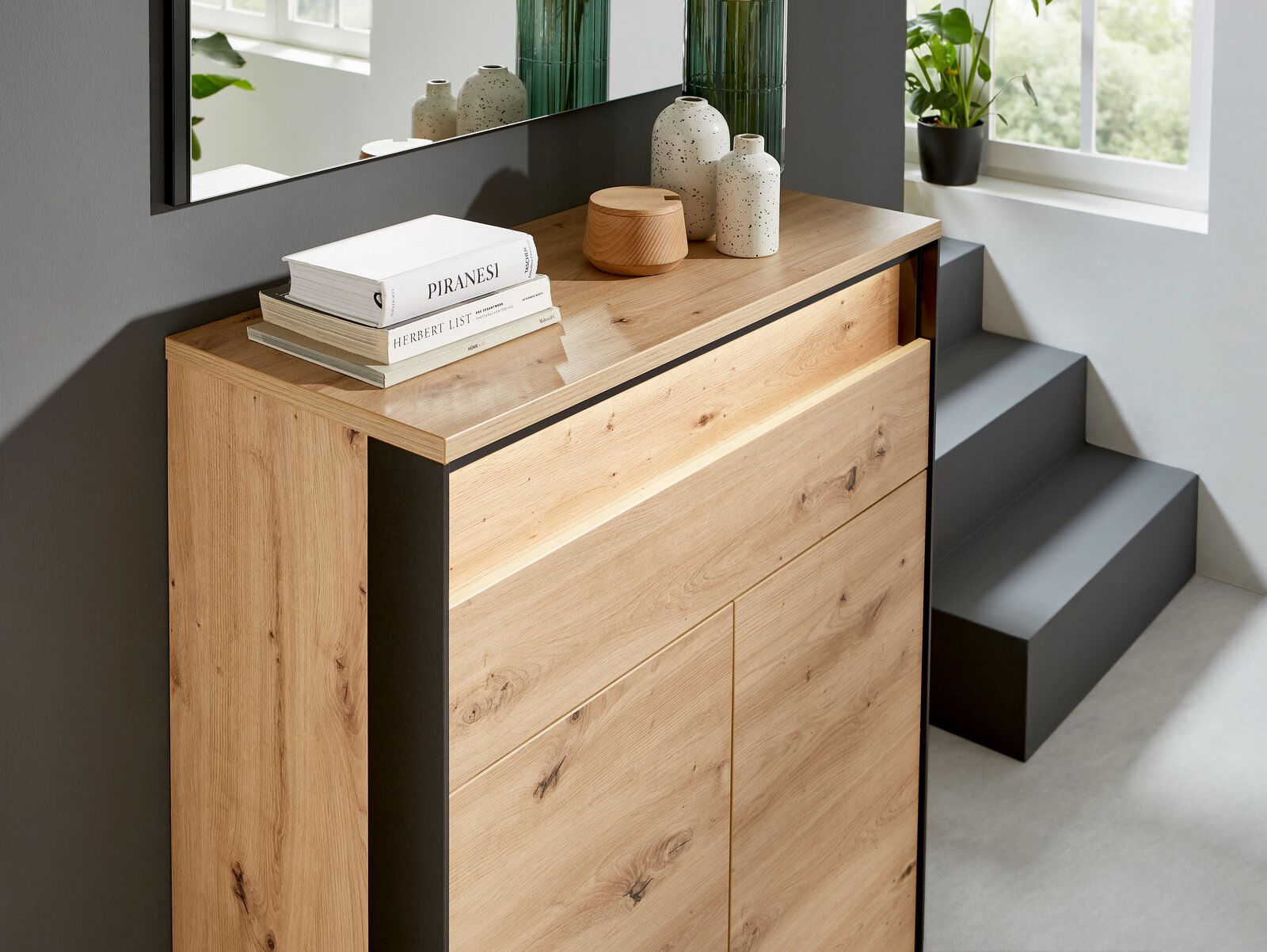 Moderner Schuhschrank aus Holz mit dekorativen Büchern und Vasen, seitliche Perspektive