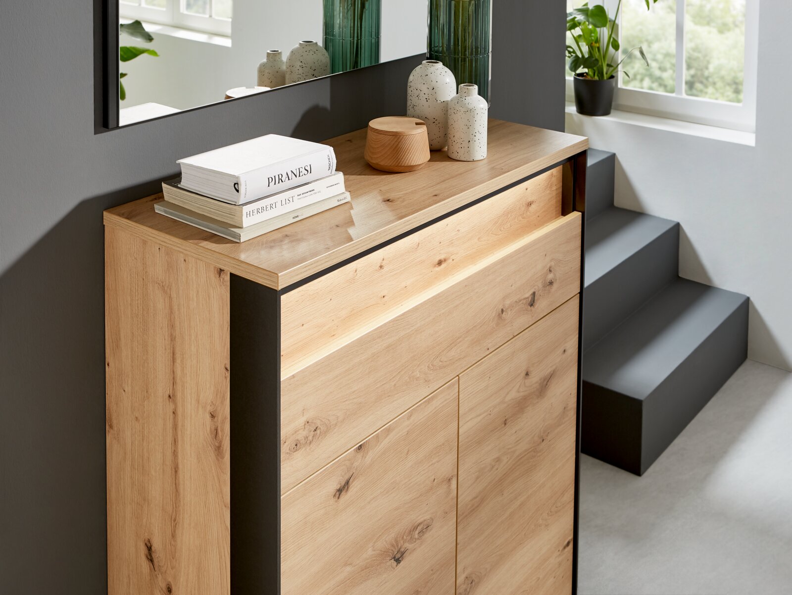 Moderner Schuhschrank aus Holz mit dekorativen Büchern und Vasen, seitliche Perspektive