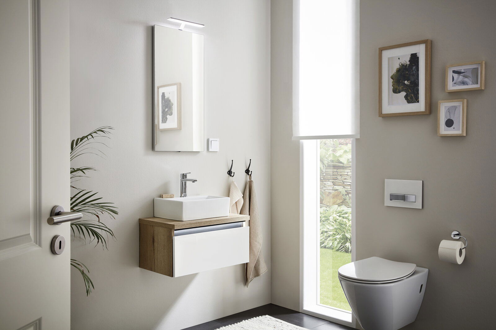 Modernes Gästebad mit hängendem Waschtisch, Spiegel mit Beleuchtung und WC, seitliche Perspektive.