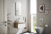 Modernes Gästebad mit hängendem Waschtisch, Spiegel mit Beleuchtung und WC, seitliche Perspektive.