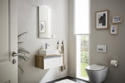 Moderne gastenbadkamer met hangende wastafel, spiegel met verlichting en toilet, zijaanzicht.