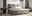 Modernes Boxspringbett in grauem Stoff mit hohem Kopfteil, dekoriert mit Kissen und Decke, seitliche Perspektive