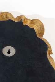 Nahaufnahme einer Wandleuchte mit unregelmäßiger goldener Kante und schwarzer Oberfläche, Rückansicht mit Schlüsselloch.