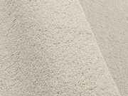 Nahaufnahme eines cremefarbenen Uni-Teppichs mit weicher, flauschiger Textur, seitliche Perspektive