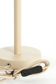 Nahaufnahme eines beigen Lampenfußes mit rundem Sockel und beige ummanteltem Kabel, seitliche Perspektive.