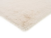 Nahaufnahme eines weichen, cremefarbenen Fellteppichs aus der Seitenperspektive.