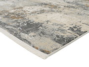 Designer Teppich mit abstraktem Muster in Grau- und Beigetönen, perspektivisch von der Seite fotografiert.