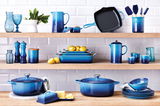Blaue Pfeffermühle in einem stilvollen Küchenregal, umgeben von passendem Geschirr und Küchenutensilien, seitliche Perspektive.