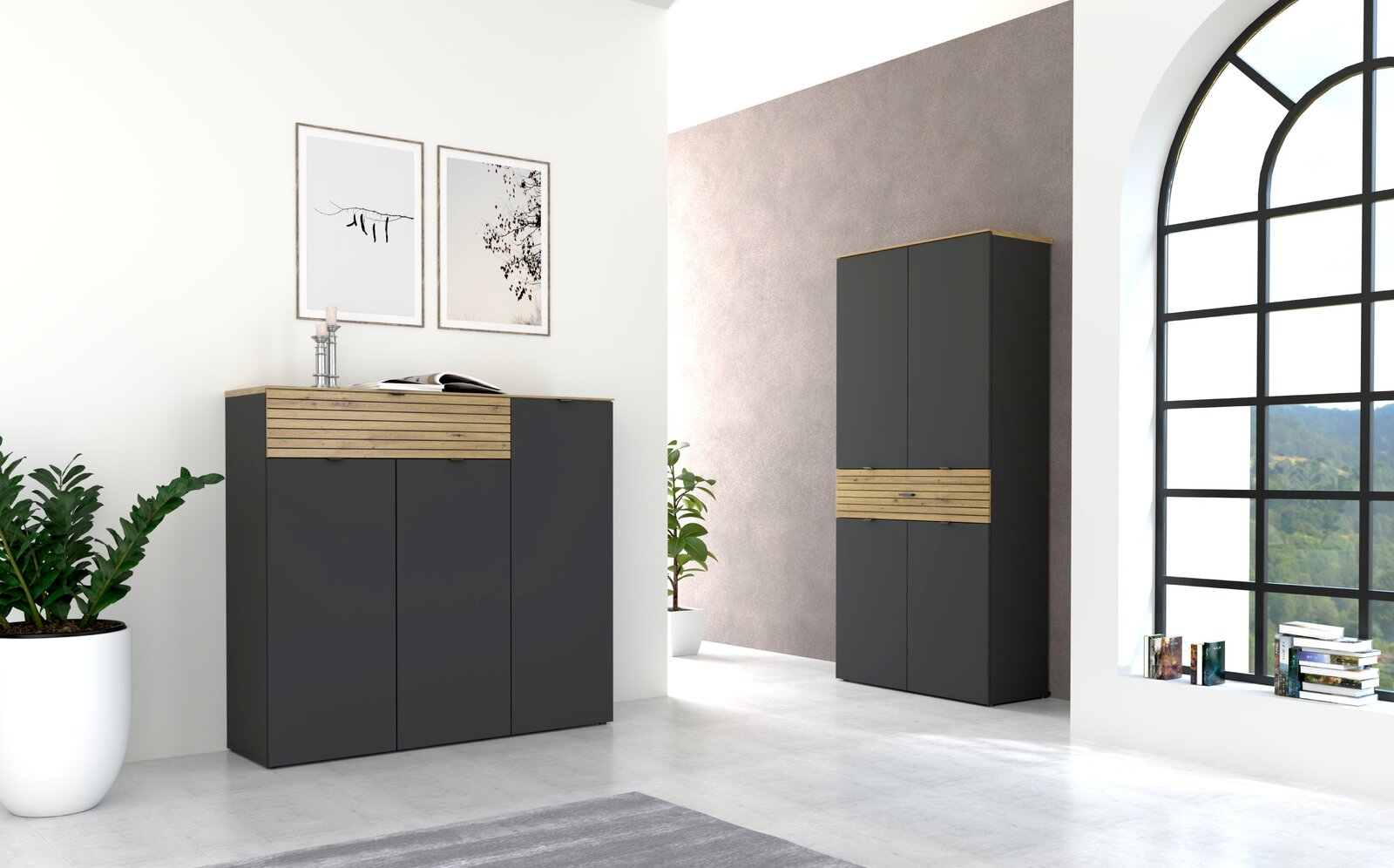 Voleo XL-Schuhschrank hoch DIANA Moderne Garderobenmöbel in Graphit mit Holzdetails, bestehend aus einem niedrigen und einem hohen Schrank, in einem hellen Raum mit großen Fenstern, Pflanzen und Wanddekorationen. Perspektive von vorne links.