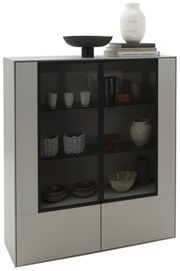 Modernes Highboard mit Glastüren, gefüllt mit dekorativen Keramiken und Büchern, aus einer frontalen Perspektive betrachtet.