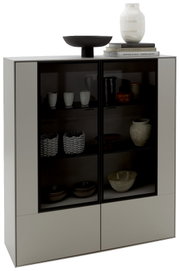 Modernes Highboard mit Glastüren, gefüllt mit dekorativen Keramiken und Büchern, aus einer frontalen Perspektive betrachtet.