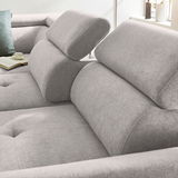 Nahaufnahme eines grauen Ecksofas mit verstellbaren Kopfstützen, weicher Polsterung und einem modernen Design. Perspektive von der Seite.