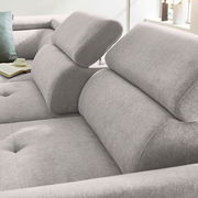 Nahaufnahme eines grauen Ecksofas mit verstellbaren Kopfstützen, weicher Polsterung und einem modernen Design. Perspektive von der Seite.