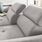 Nahaufnahme eines grauen Ecksofas mit verstellbaren Kopfstützen, weicher Polsterung und einem modernen Design. Perspektive von der Seite.