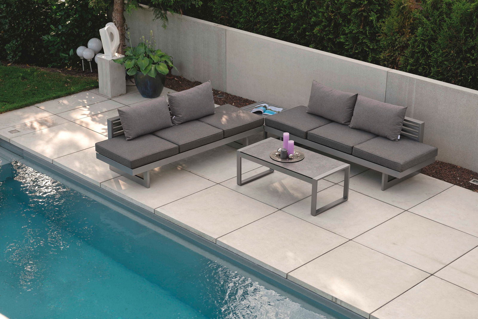 Moderne Lounge-Möbel auf einer Terrasse neben einem Pool, aus der Vogelperspektive fotografiert.