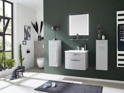 Moderner Badblock 3-teilig in grauer Farbe, bestehend aus einem Waschbeckenunterschrank, einem Hängeschrank und einem Hochschrank, vor einer dunkelgrünen Wand. Perspektive: Frontalansicht.