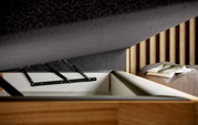 Nahaufnahme eines Boxspringbetts mit geöffneter Bettkastenfunktion, die den Stauraum und die Hebemechanik zeigt. Perspektive von der Seite.