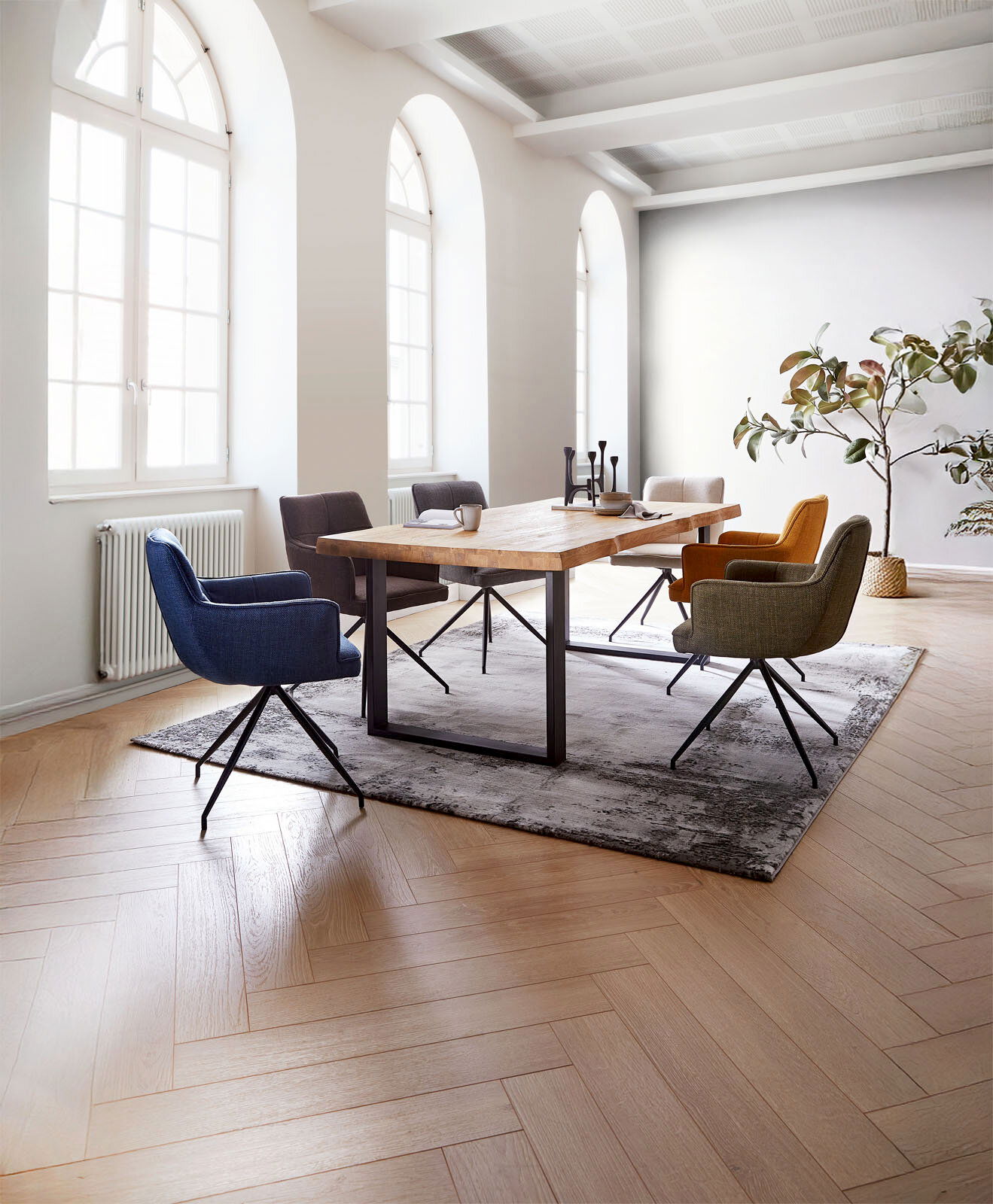 Valdera Tischplatte 200x100 MEMORY Esszimmer mit einem großen Holztisch und sechs farbigen Armlehnstühlen, seitliche Perspektive