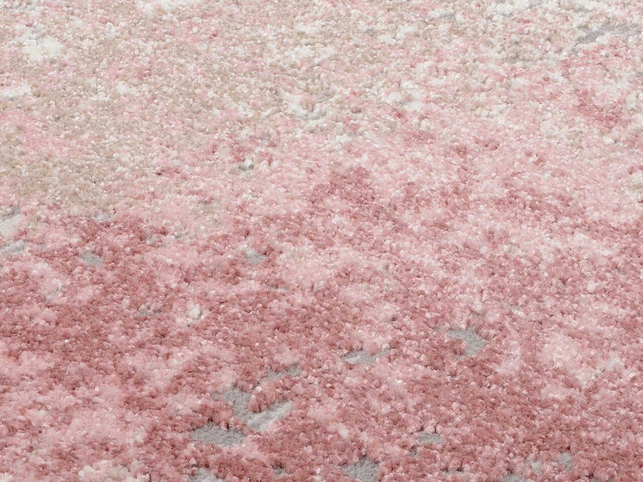 Nahaufnahme eines Designer-Teppichs in Rosa- und Beigetönen mit flauschiger Textur, von oben betrachtet.