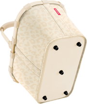 Unterseite einer beigefarbenen Reisenthel-Tasche mit dezentem Leopardenmuster, verstärktem Boden und schwarzen Standfüßen, schräg von unten fotografiert