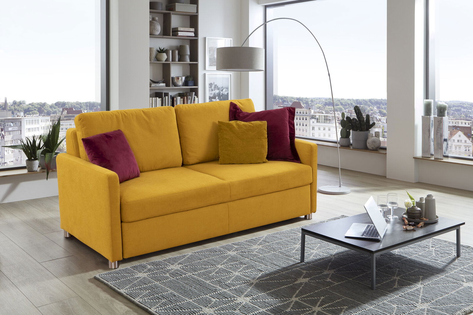 Gelbes Funktionssofa mit roten und gelben Kissen in einem modernen Wohnzimmer, seitliche Perspektive