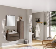 Moderne badkamerkast in donkere houtlook, rechts aan de muur bevestigd, met decoratieve elementen en een spiegel op de voorgrond, gezien vanaf de zijkant.